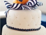 a white buttercream wedding cake with a striped ribbons and a pumpkin on top is a lovely idea for a fall nautical wedding