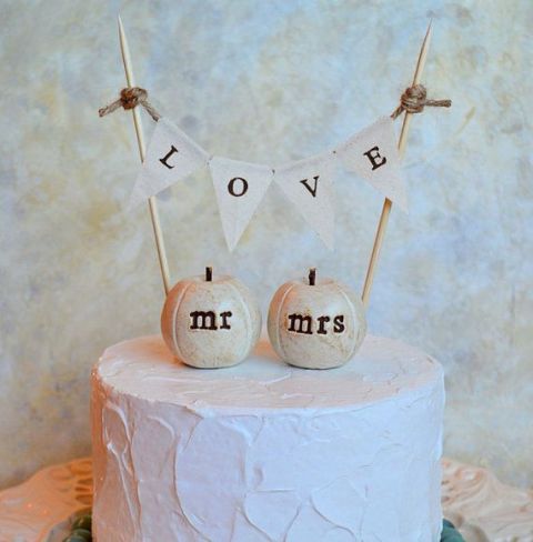 a white buttercream wedding cake with mini sugar pumpkins and a banner is a lovely and cozy idea for a rustic wedding