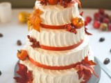 a white textural buttercream wedding cake decorated with bright fall leaves and pumpkins is a fun and cool idea