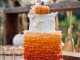 a cool fall wedding cake with white birchbark and ruffle orange tiers, with sugar blooms and a pumpkin on top is a very cute and sweet idea