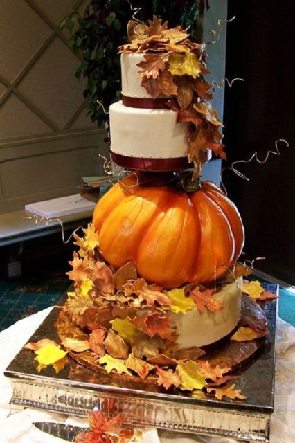 a creative wedding cake with white and a sugar pumpkin tiers, with bright leaves and twigs is a very fun and lovely idea