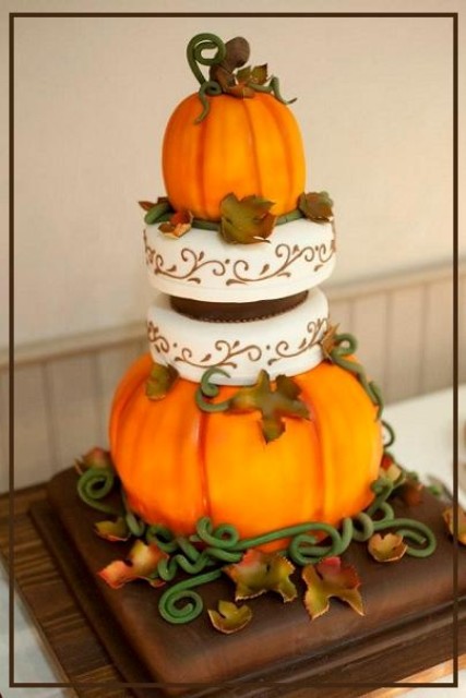 a creative wedding cake with white patterned tiers, orange pumpkins, faux leaves and twigs on top is a lovely idea