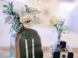 a vintage cluster wedding centerpiece of simple blooms in vases, a vintage camera and a chalkboard table number is a lovely idea
