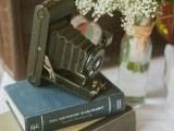 a vintage wedding centerpiece of a stack of vintage books, a camera and white blooms in a jar is a lovely idea for a chic vintage wedding