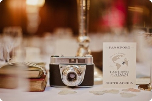 a vintage camera wedding centerpiece of a stack of books, a vintage camera and a table name is a great idea