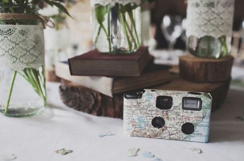 a rustic cluster wedding centerpiece of books, a vintage camera wrapped with map and blooms in vases