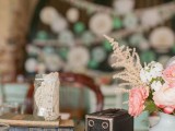 a cluster vintage wedding centerpiece of a stack of books, a vintage camera, a vase with pink and white blooms is chic