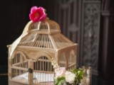 a small vintage cage with a bright pink bloom on top is a lovely solution for an exquisite vintage wedding