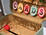 a vintage mint-colored suitcase with a colorful banner and bright beads and embellishments is a cool idea for a vintage or retro wedding