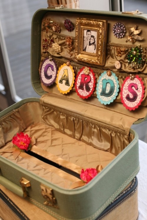 a vintage mint-colored suitcase with a colorful banner and bright beads and embellishments is a cool idea for a vintage or retro wedding