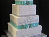 a white wedding cake with edible metallic embellishments and tiffany blue ribbons and bows