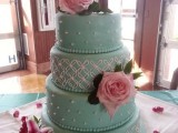a romantic tiffany blue wedding cake with white patterns and beads, pink roses and a pretty topper