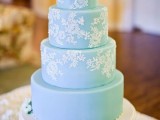 a romantic tiffany blue wedding cake decorated with white lace patterns and with fresh white blooms on top