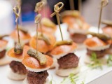a white tray with greenery and mini burgers on skewers is a cool idea for a modern wedding
