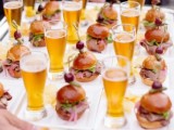 a silver tray with mini burgers with olives and salami on skewers and mini beer glasses