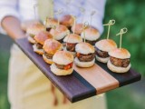 a striped wooden tray with burgers on skewers is a comfy and stylish way to serve them
