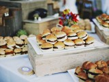 a rustic station with wooden boxes and trays and lots of mini burgers on skewers are a great idea for a farmhouse or just casual wedding