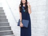 a modern navy sleeveless dress with an asymmetrical skirt, a matching clutch, silver shoes and a statement necklace