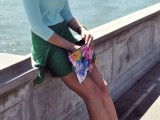 a light blue top, a green wap mini skirt, green platform shoes and a colorful floral print clutch