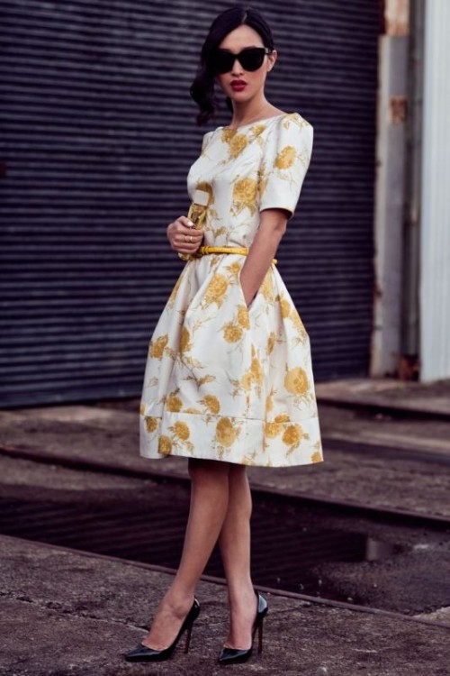 a white and yellow over the knee dress with short sleeves, black heels and a small clutch
