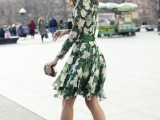 a green and white floral print short dress with a high neckline and long sleeves, silver shoes and a geometric clutch