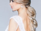 a blonde low ponytail with curtains bangs, a braided halo, waves is a very refined and chic hairstyle for a formal bridal look
