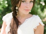 a messy partly braided low ponytail with a bump on top and some locks down, waves and a tiny braid is a cool idea for a boho bride