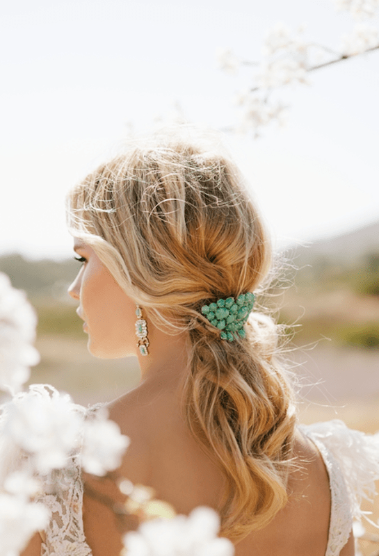 a low messy and wavy ponytail accented with a turquoise barette is a lovely idea for a beach or boho bride