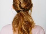 a twisted and textural low messy ponytail with a volume on top and some locks framing the face for a casual bridal look