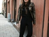 a black jumpsuit with a covered plunging neckline, a gold and black shiny cropped jacket