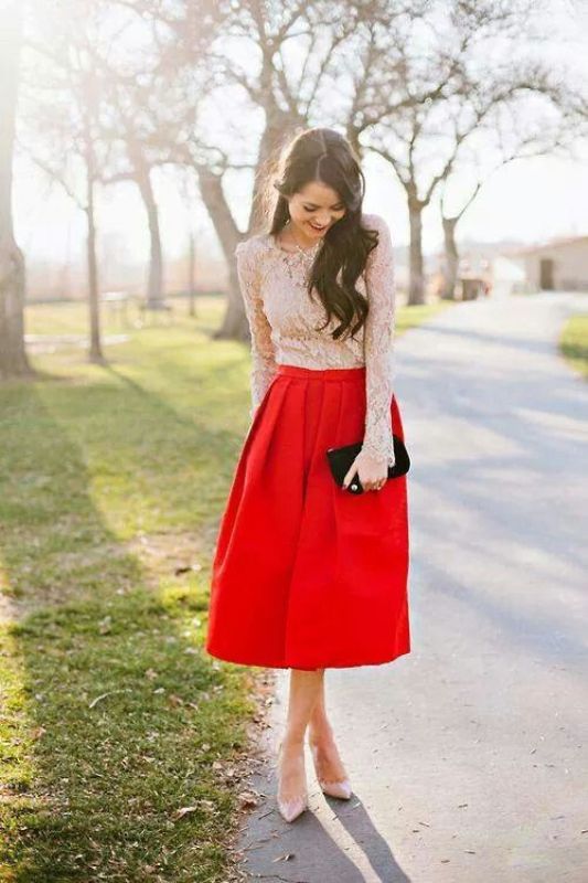 A white lace top with long sleeves, a red A line midi skirt, blush heels and a black clutch
