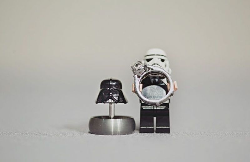 A Stormtrooper holding a wedding ring and a Darth Vader helmet with another ring for showing off your jewelry in a cool way