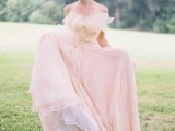 a tender light pink off the shoulder wedding dress with a ruffle neckline and a layered skirt plus a train is a very delicate and chic option