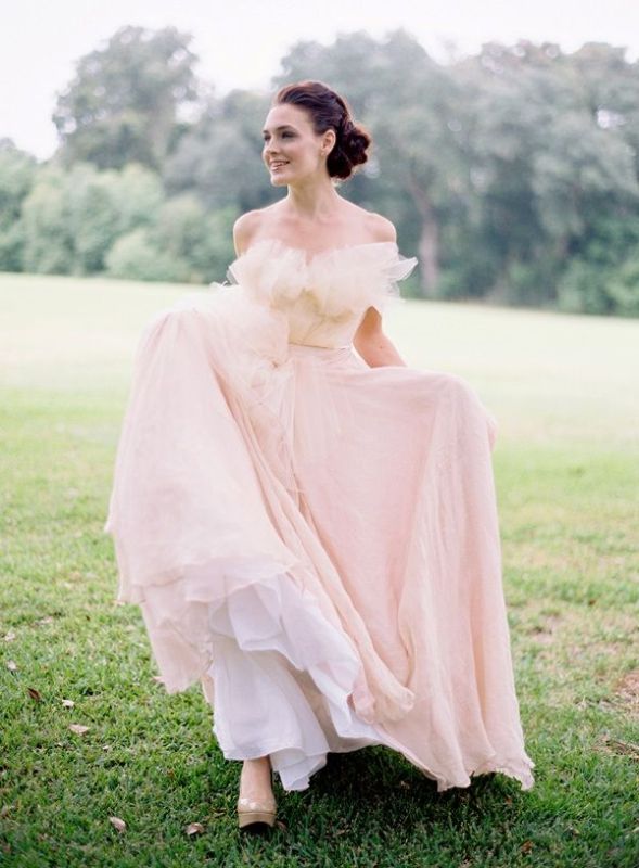 A tender light pink off the shoulder wedding dress with a ruffle neckline and a layered skirt plus a train is a very delicate and chic option