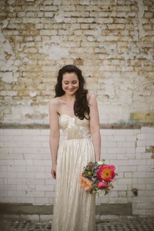 a shiny gold strapless A-line wedding dress with a draped bodice and a pleated skirt is a chic and shiny glam option
