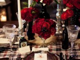a plaid table runner paired with red roses, candles and chic plates for a stylish winter or Christmas wedding