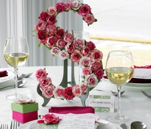 a monogram covered with pink roses can be a nice part of a wedding centerpiece