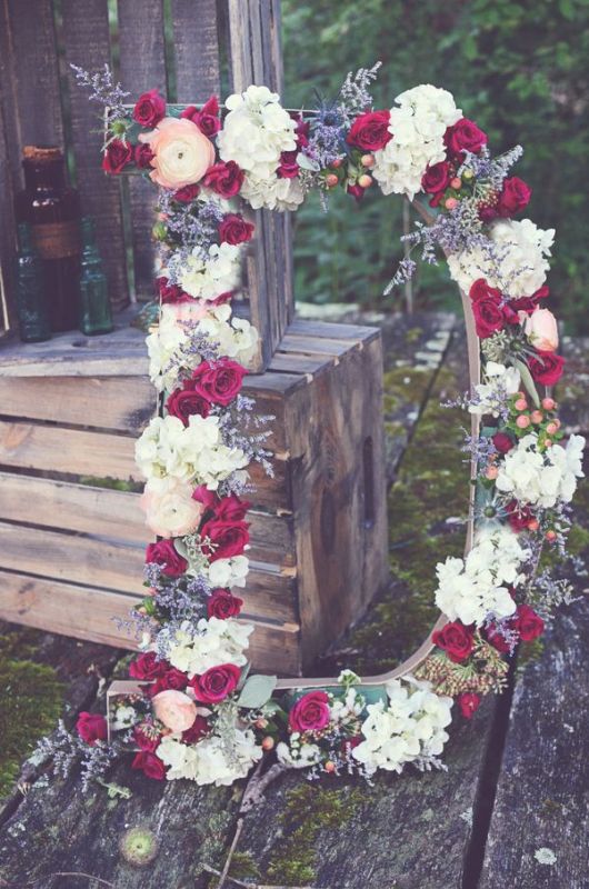 a large monogram covered with burgundy and white blooms and greenery