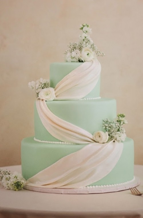 a light green wedding cake with white sugar decor and white fresh blooms is a stylish and chic idea for a spring or summer wedding
