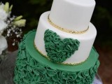 a white and emerald wedding cake with a ruffle tier and a ruffle heart plus touches of gold is refined and chic