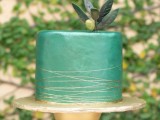 a green sleek wedding cake topped with sugar foliage and a sugar olive plus gold stripes is a gorgeous idea