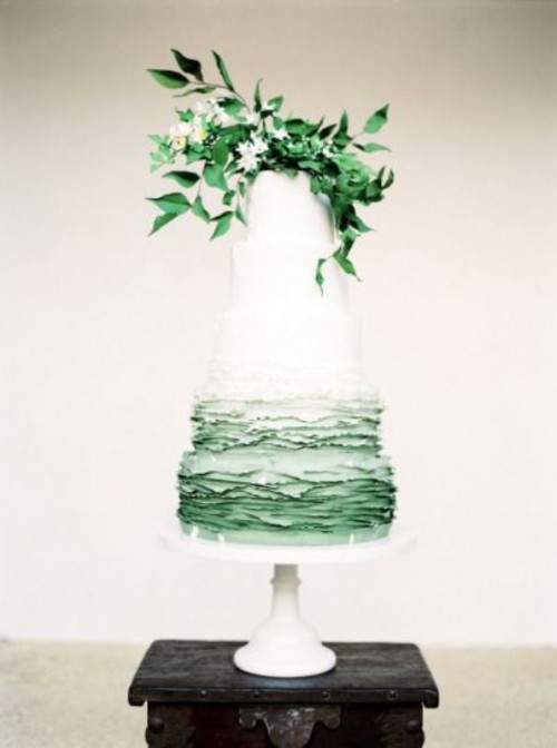 a chic wedding cake with white and ombre freen ruffle tiers, with greenery and white blooms for a spring or summer wedding