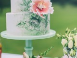 a white wedding cake with green floral patterns and a pink sugar bloom is a bold idea for a botanical wedding