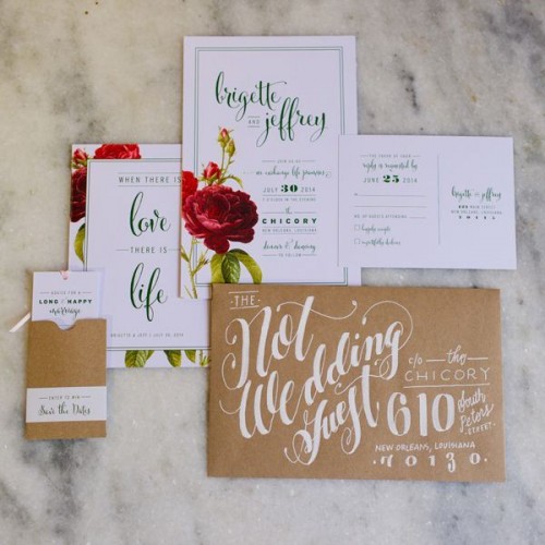 a neutral Valentine's Day wedding invitation suite with black calligraphy, red roses and a kraft paper envelope