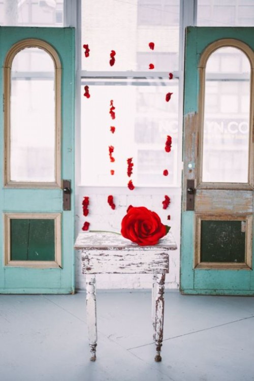 an oversized red rose instead of a large wedding bouquet and some red petals hanging down to decorate the altar or the venue are a beautiful and classic idea