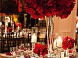 a lovely red rose wedding centerpiece of several lush arrangements and with red roses to mark each place setting is a beautiful idea