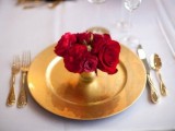 a red rose arrangement placed into a gold vase, with a gold charger and cutlery looks very romantic and very glam-like