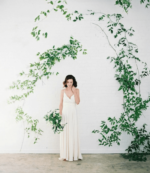 a wedding backdrop - a white brick wall and greenery branches attached in a whimsy way