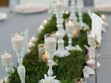 a wedding table runner with much grass, white candleholders with candles is great for a vintage-inspired wedding