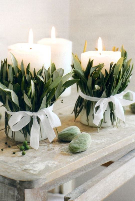 White candles wrapped with greenery and with white bows for a chic and organic look